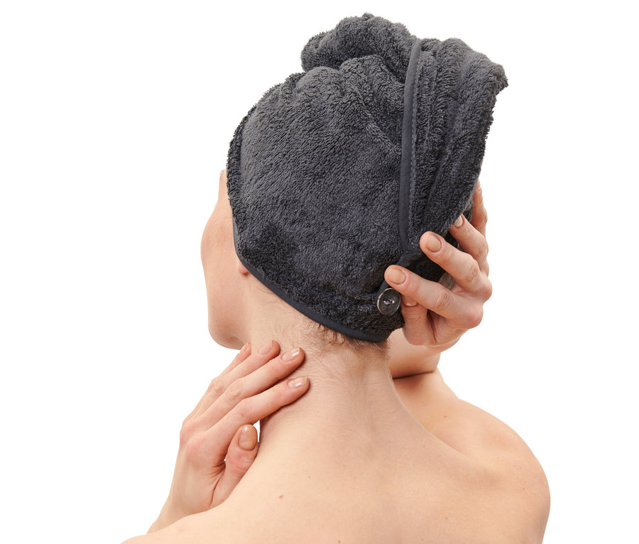 Kobieta poprawia antracytowy ręcznik-turban na głowie.