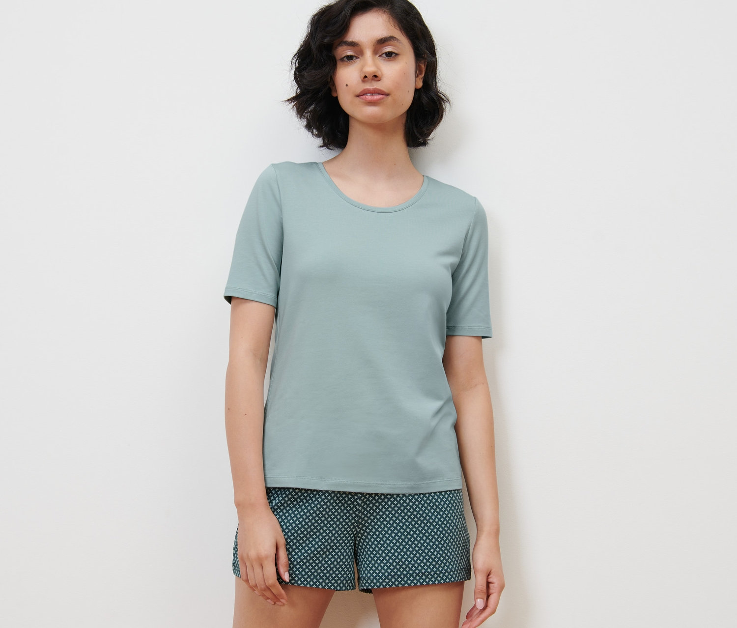 Kobieta ma na sobie piżamę z krótkimi spodenkami z wzorem na całej powierzchni.