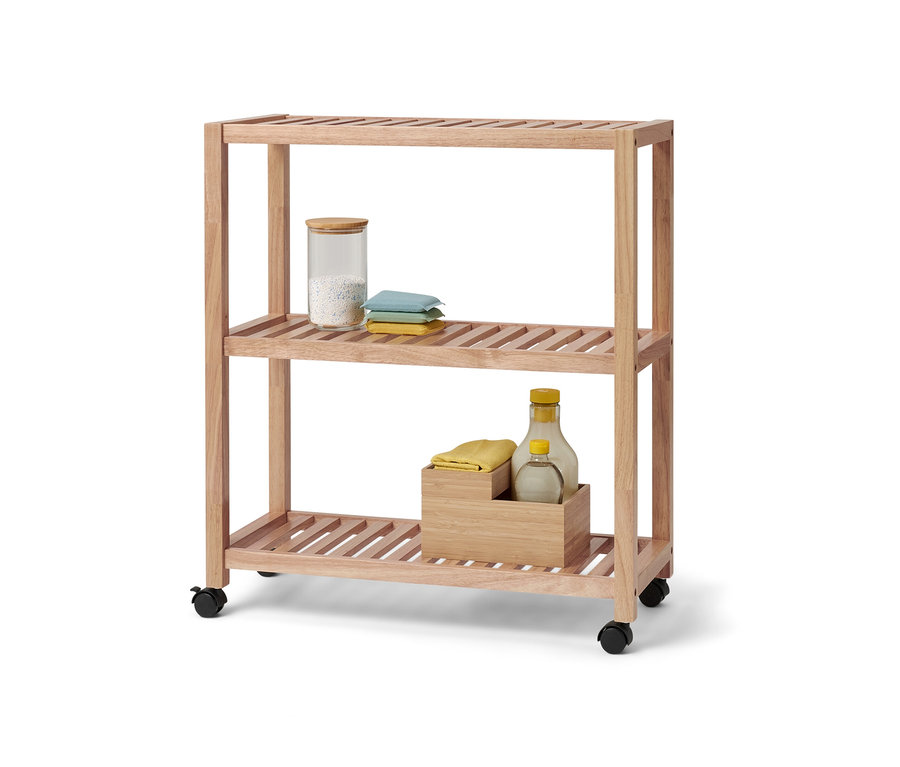 Trzypoziomowy regał z litego drewna na kółkach. Na górnej półce szklany pojemnik i tekstylia.