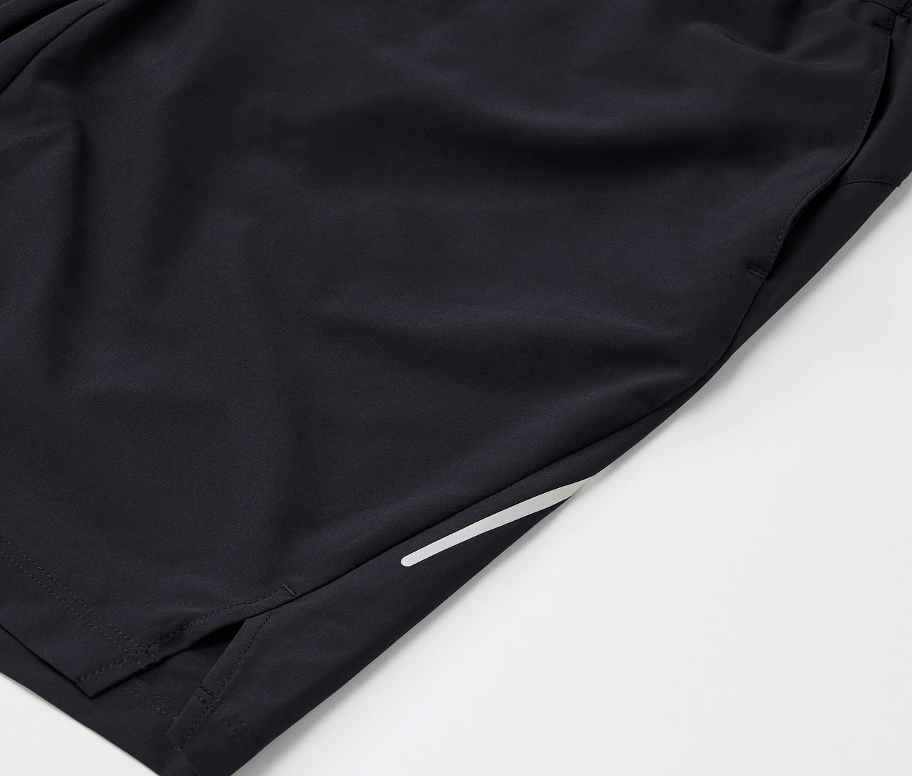 Zbliżenie na czarne spodenki sportowe z kieszenią i odblaskowym paskiem.