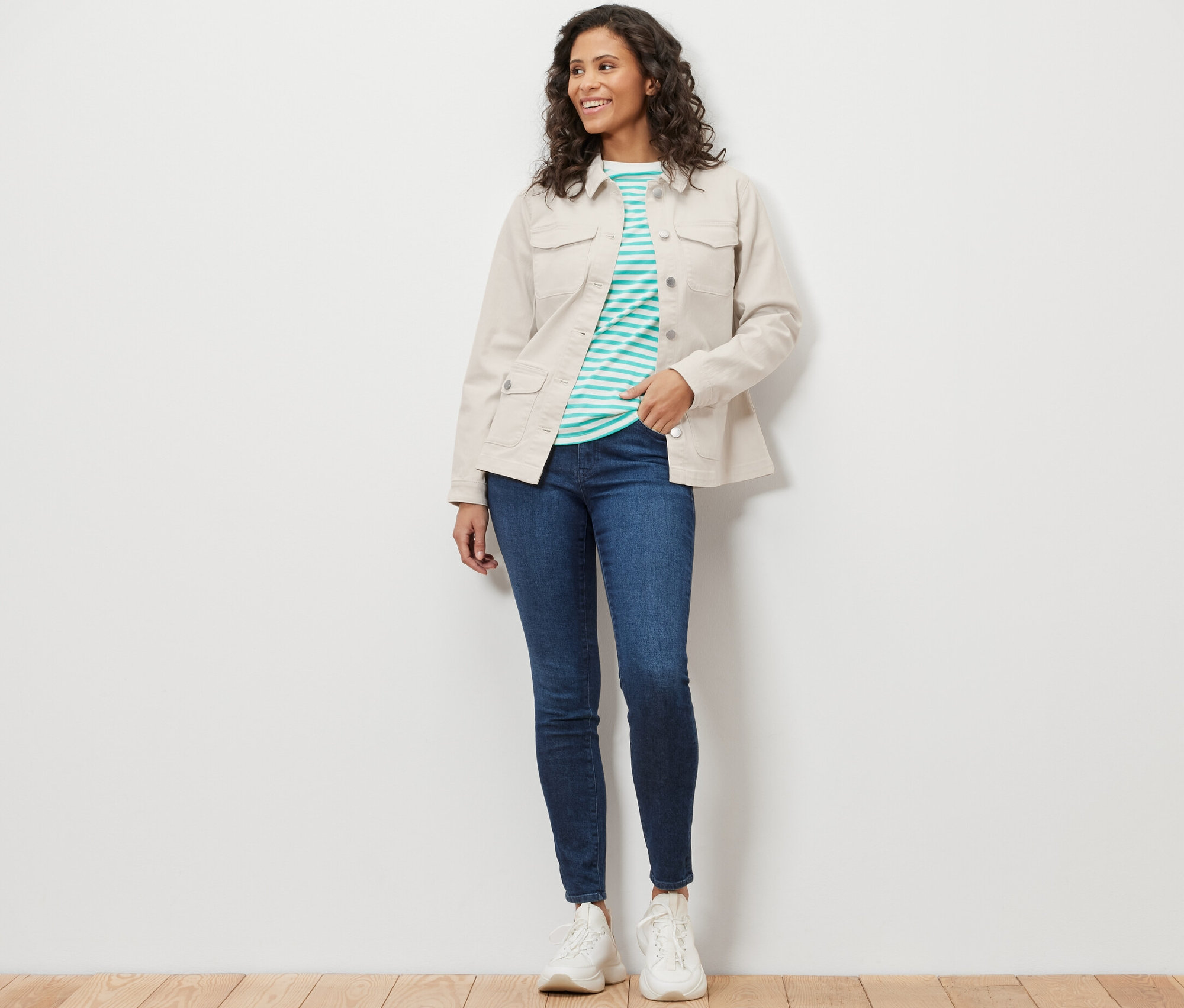 Kobieta ma na sobie kurtkę dżinsową z kieszeniami cargo, niebieskie dżinsy i białe trampki.