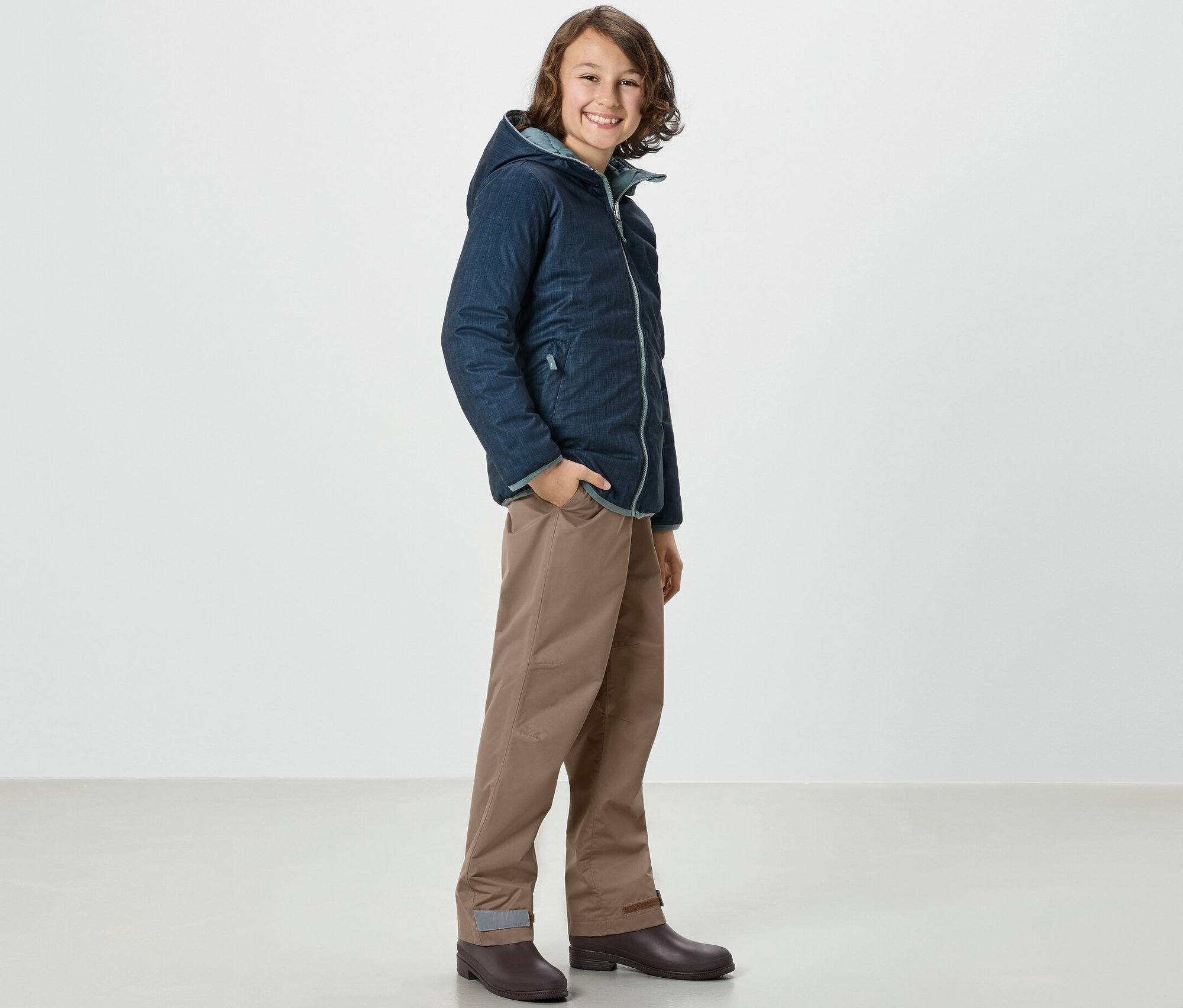 Chłopiec w kurtce i Kinder-Regenhose stoi bokiem.