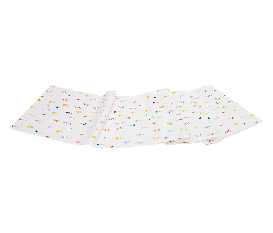 Biała tkanina ze wzorem małych, kolorowych kwiatów leży złożona na białym tle.