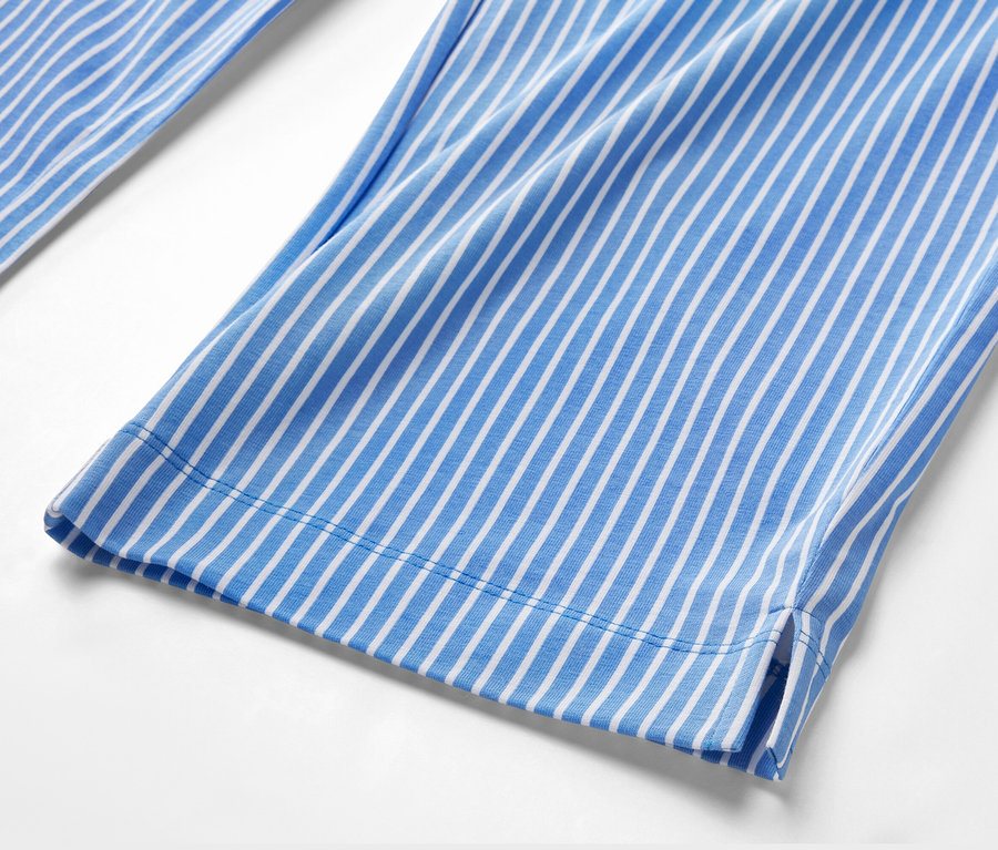 Szczegół spodni od piżamy w paski biało-niebieskie.