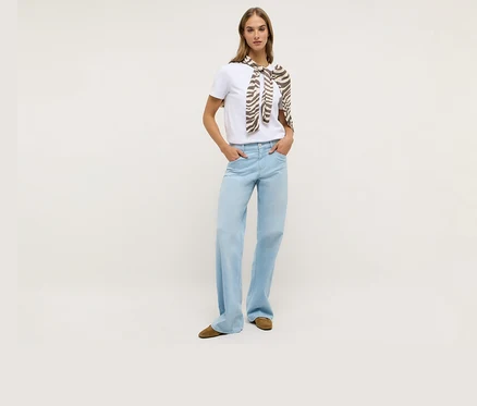Kobieta w białym T-shircie i dżinsach Angels „Liz Modern” Wide Leg. Na ramionach ma zawiązany szal w zebrę.