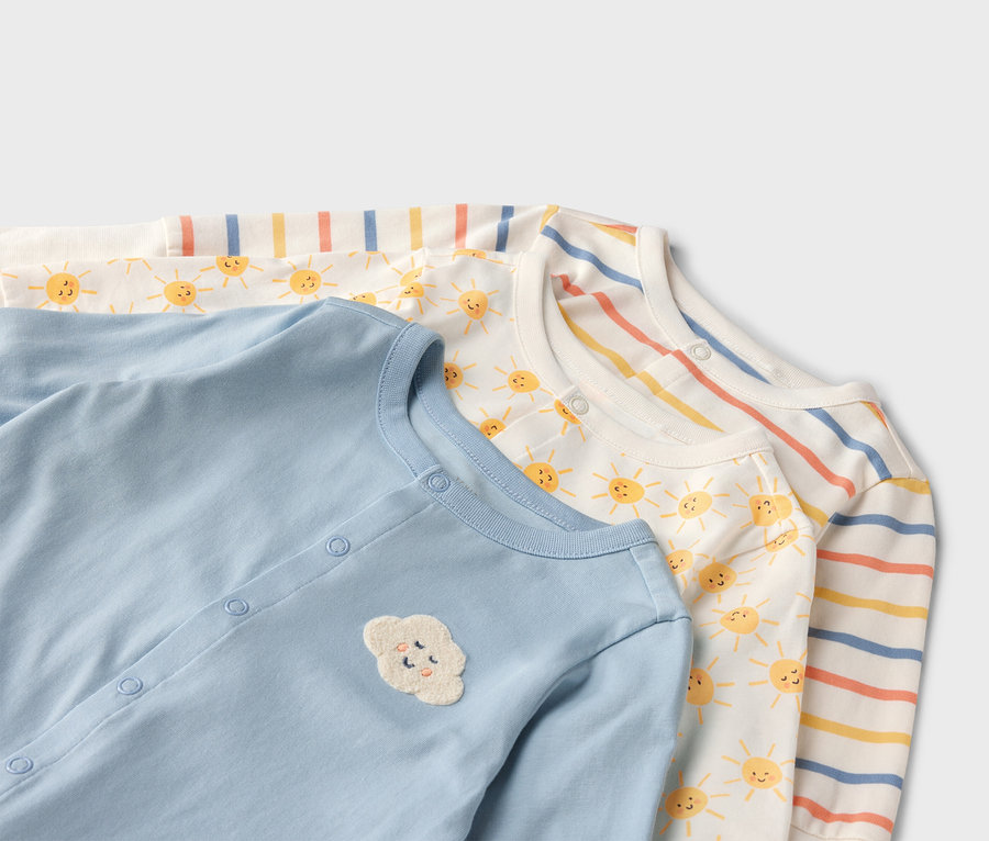 Zbliżenie na trzy pajacyki niemowlęce: jasnoniebieski z aplikacją chmurki, biały w słoneczka i w paski.