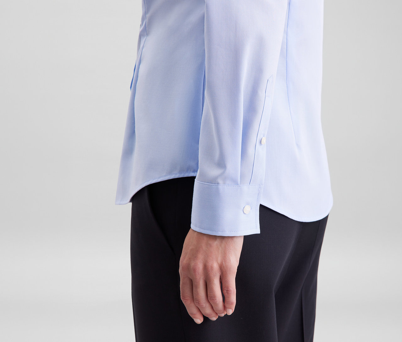 Osoba w jasnoniebieskiej bluzce Seidensticker Slim Fit non iron i czarnych spodniach.