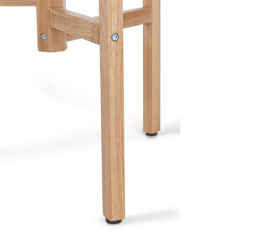 Detal drewnianej nogi krzesła lub stołka w jasnym kolorze z czarną stopką.