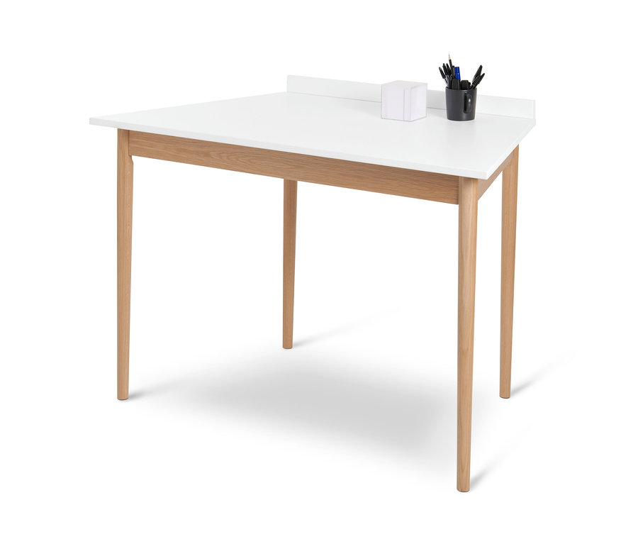 Białe biurko w kształcie trapezu z czterema drewnianymi nogami i czarnym kubkiem z artykułami piśmienniczymi.