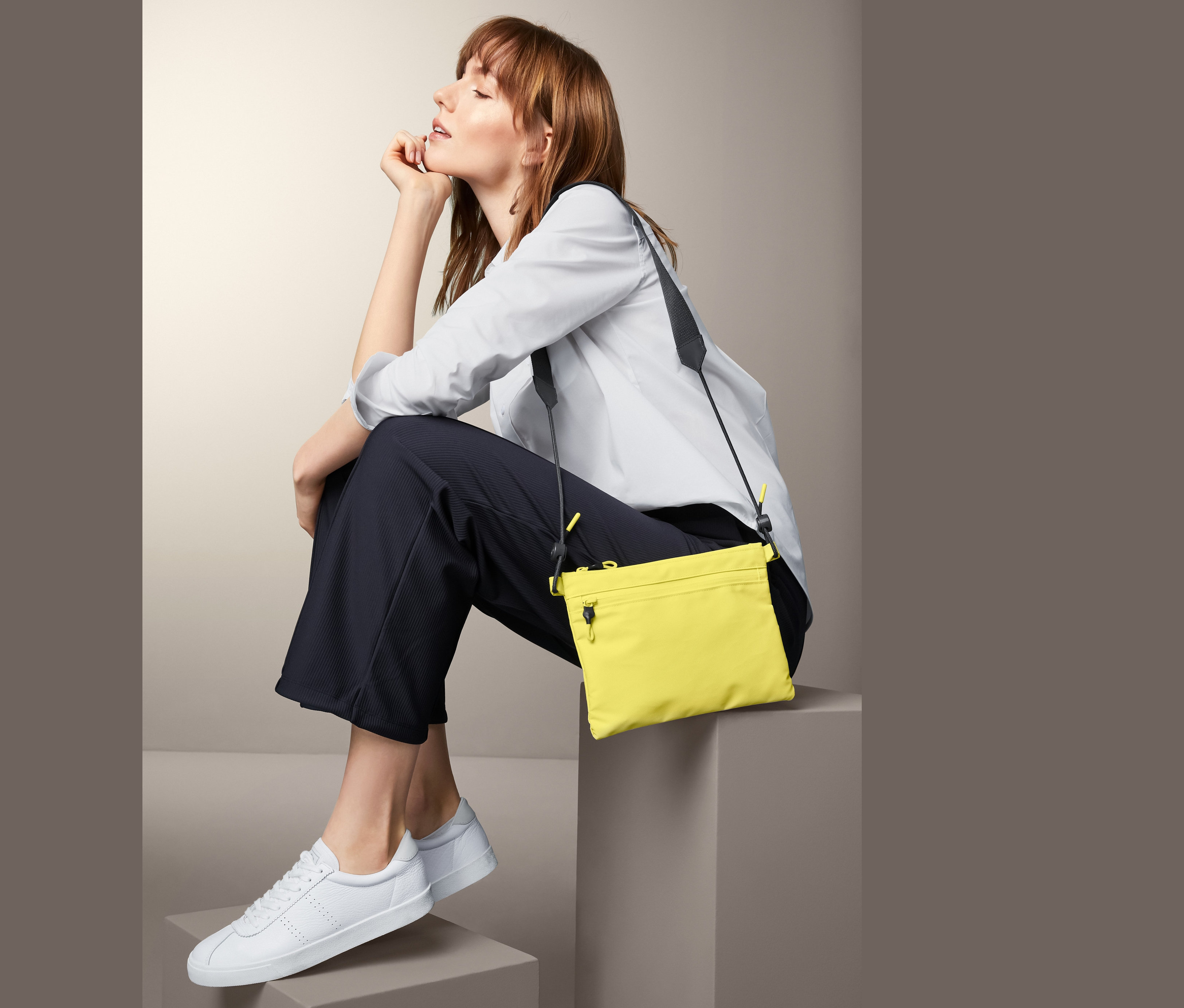 Kobieta siedzi z żółtą torbą na ramię.