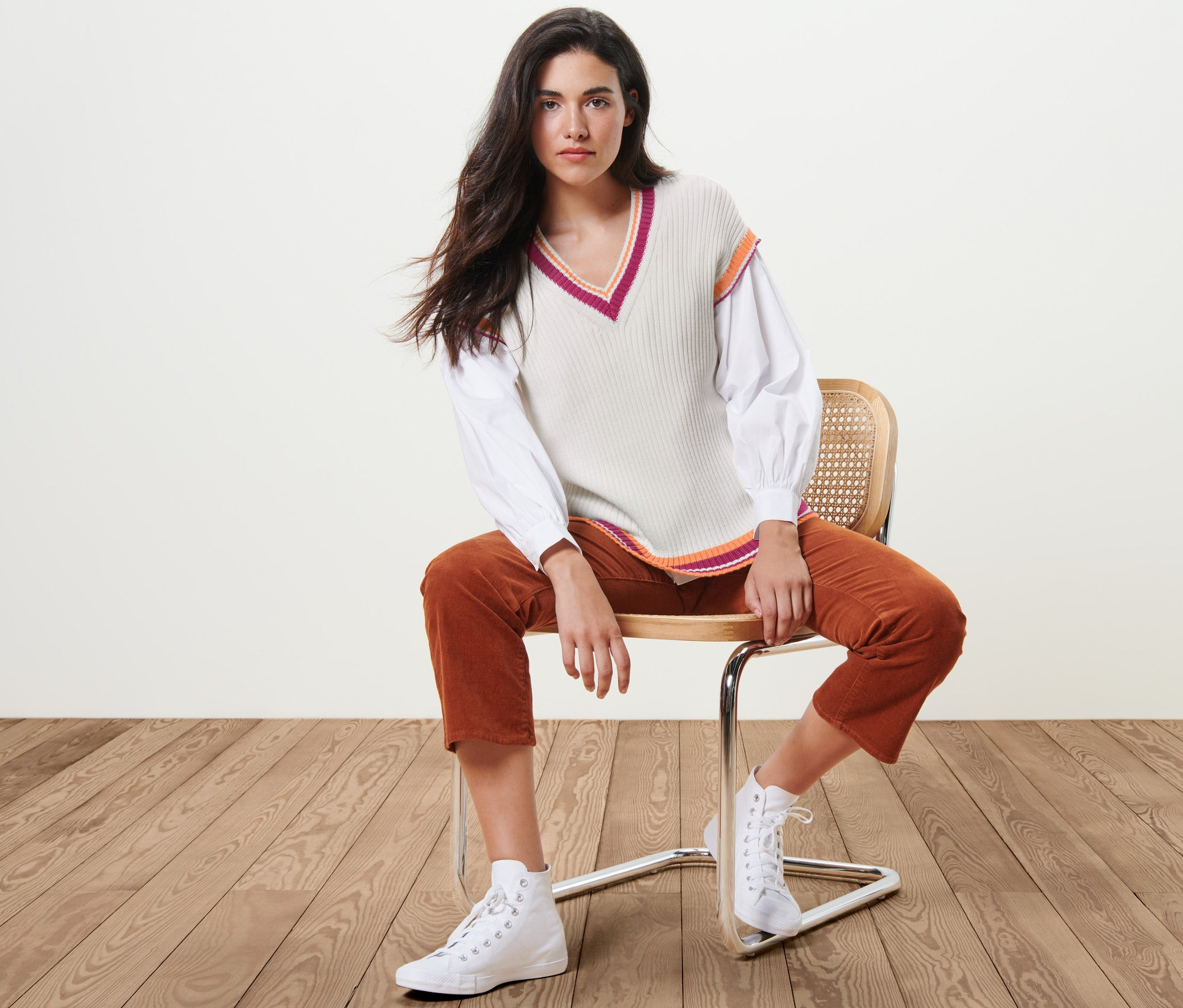 Kobieta siedzi na krześle i ma na sobie bezrękawnik dzianinowy.