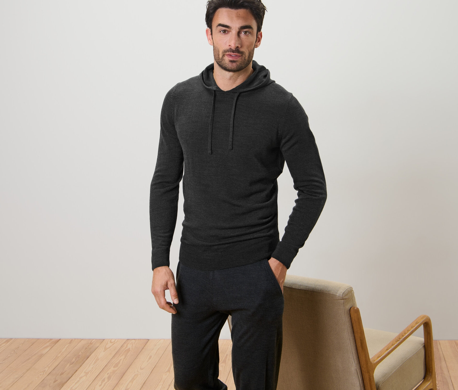 Mężczyzna pozuje w swetrze z kapturem.