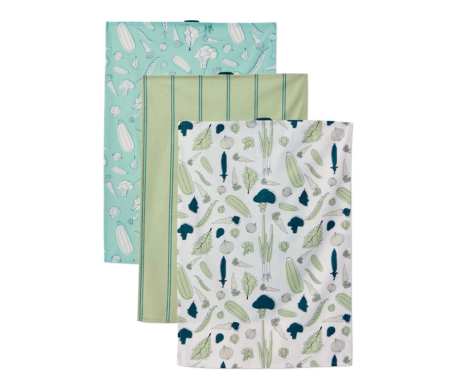 Trzy ściereczki kuchenne o różnych wzorach. Jedna jasnoniebieska z warzywami, jedna zielona w paski i jedna biała z warzywami.