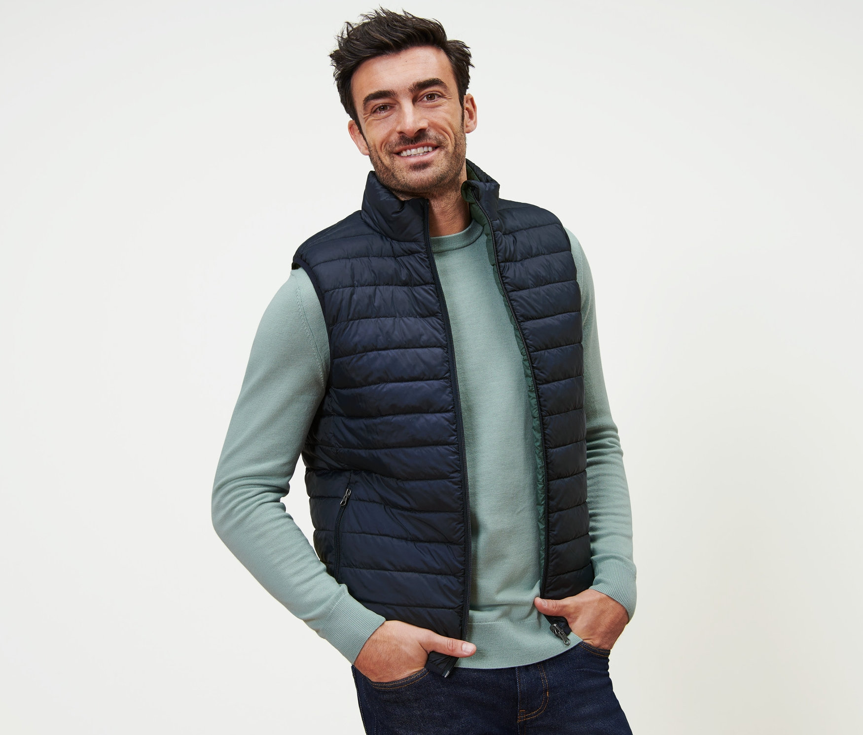 Uśmiechnięty mężczyzna pozuje w granatowej kamizelce dwustronnej.