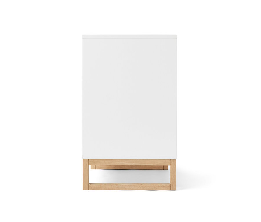 Biała szafka pod umywalkę z drzwiczkami i boczną przegródką.