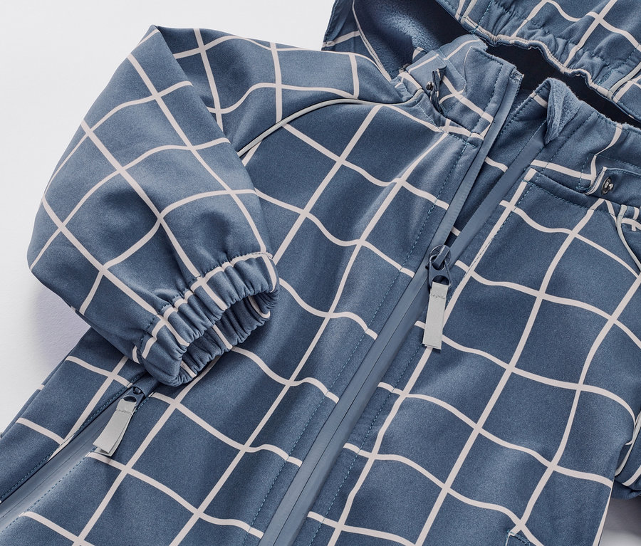 Zbliżenie na dziecięcy kombinezon softshell w kratkę z zamkiem błyskawicznym.