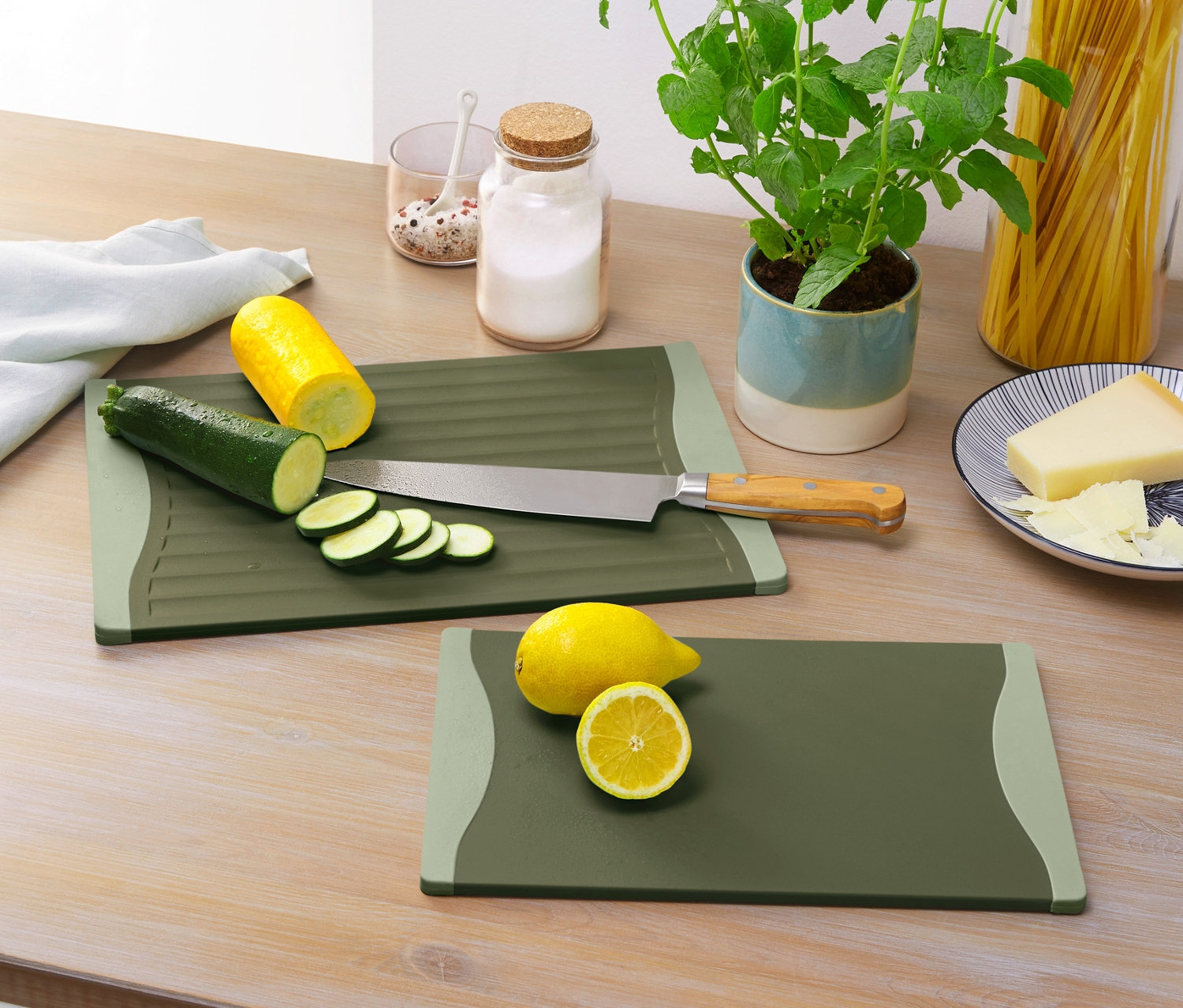 Dwie deski do krojenia z pokrojoną cukinią, żółtą cukinią i cytryną na drewnianym stole.