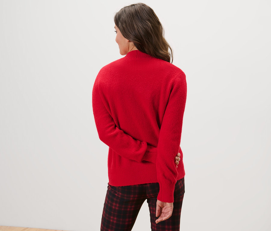 Widok z tyłu na kobietę w czerwonym rozpinanym swetrze.