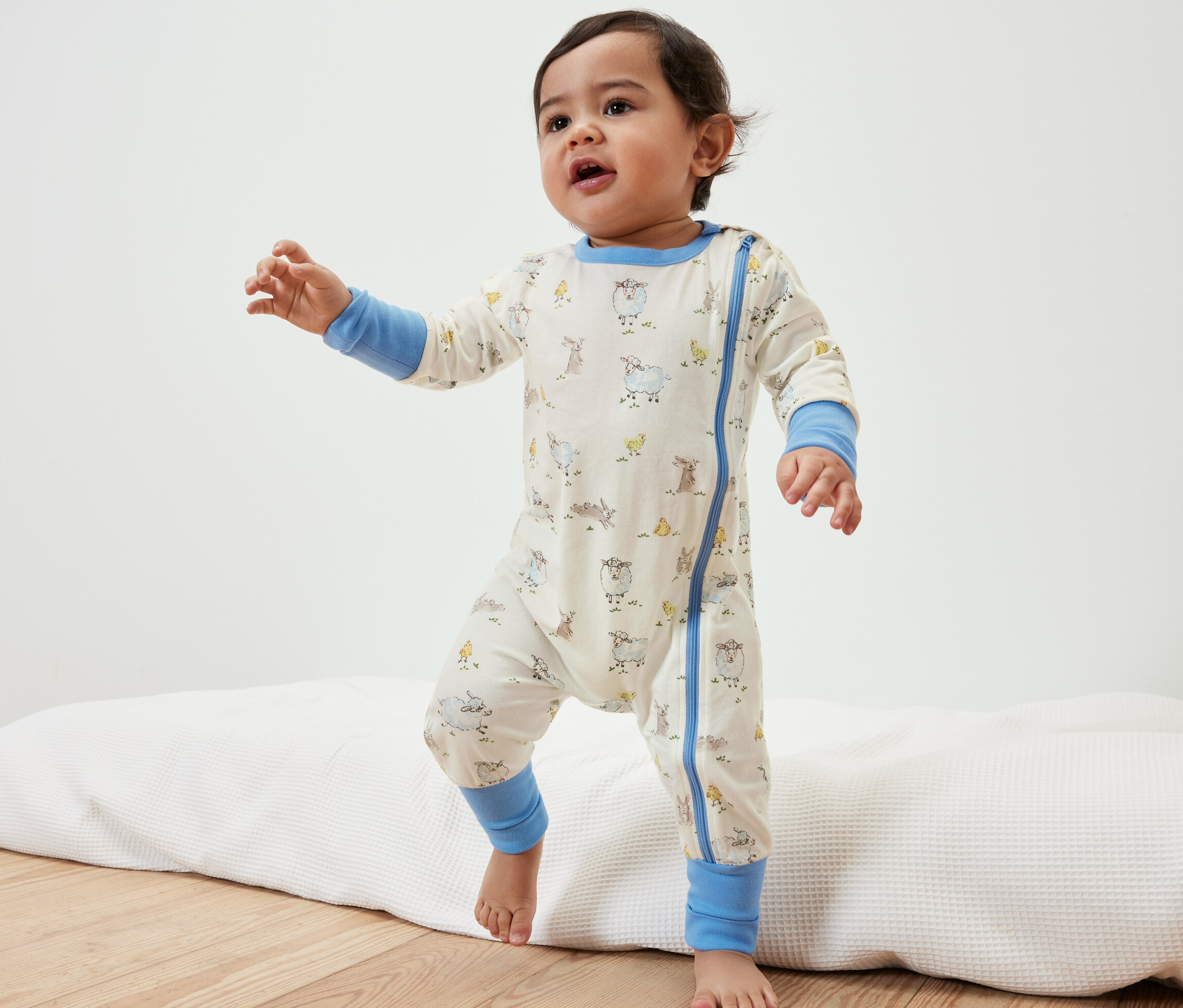 Małe dziecko w piżamie w zwierzątka stoi na podkładce.