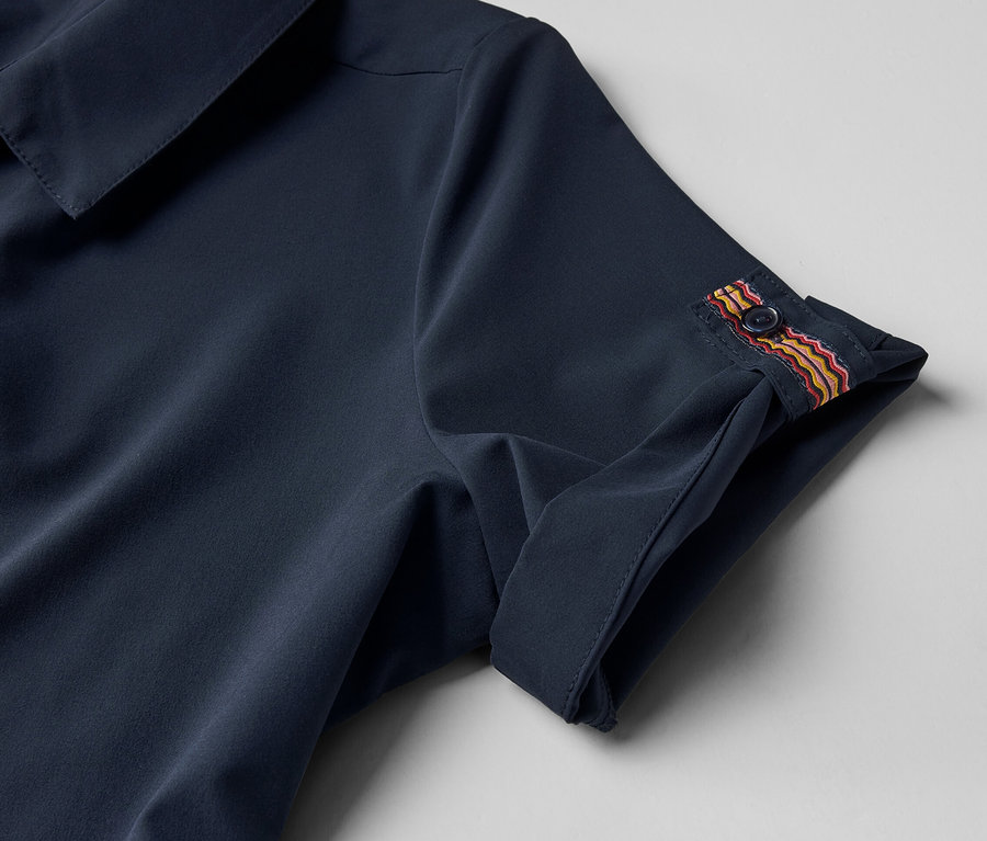 Detal sukienki funkcyjnej z guzikiem na rękawie.