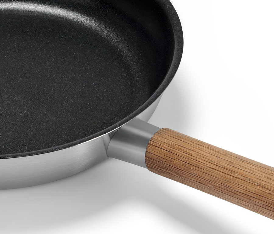 Fragment patelni ze stali nierdzewnej z drewnianą rączką.