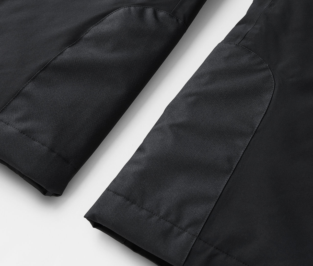 Zbliżenie na nogawki czarnych spodni z kontrastowymi panelami.