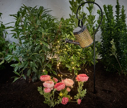 Lampa solarna „konewka” umieszczona w rabacie kwiatowej.