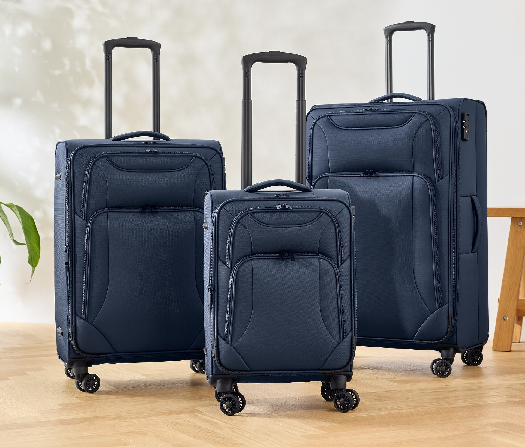 Trzy niebieskie walizki tekstylne stoją na podłodze.