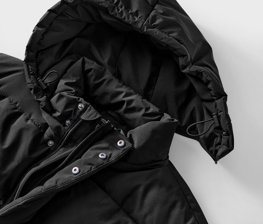 Zbliżenie na czarną kurtkę puchową z kapturem i zamkiem błyskawicznym.