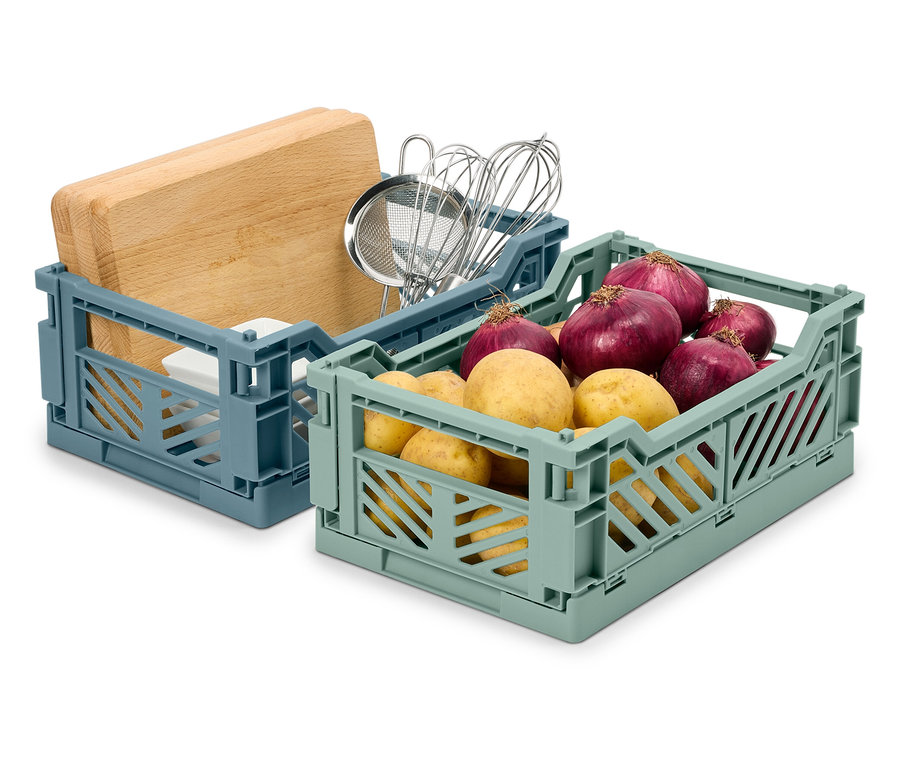 Dwa składane pudełka: niebieskie z deską do krojenia i przyborami kuchennymi, zielone z ziemniakami i cebulą.