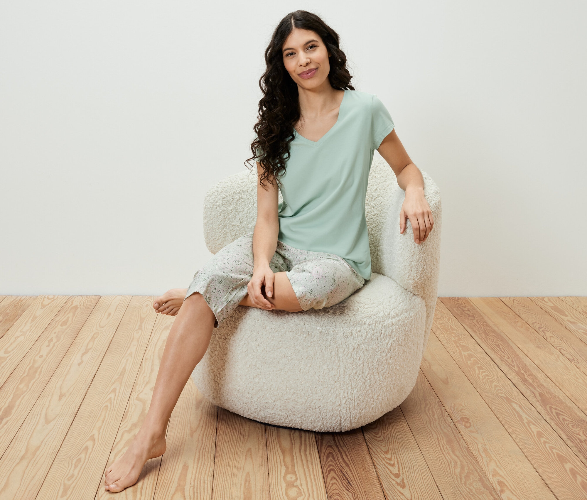 Kobieta siedzi w fotelu i ma na sobie jasnozielony zestaw piżamy 3/4.