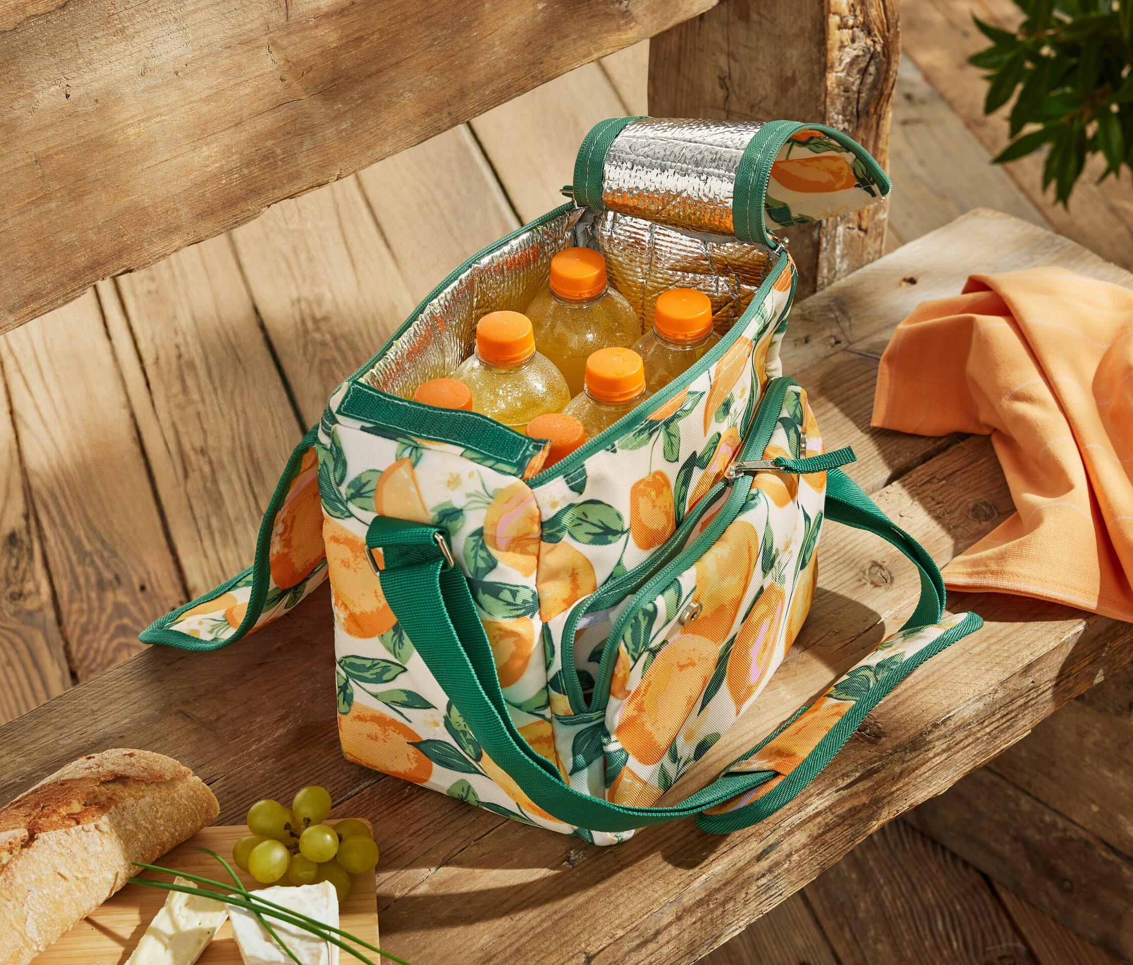 Otwarta minitorba termiczna we wzór cytrusowy wypełniona butelkami na drewnianej ławce.
