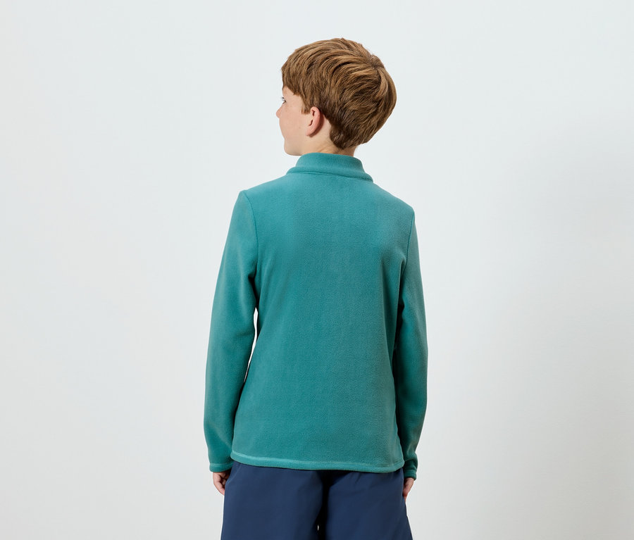 Z tyłu widoczna jest osoba z krótkimi brązowymi włosami, ubrana w niebiesko-zieloną bluzkę z długim rękawem i granatowe szorty.