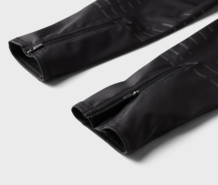 Szczegół czarnych spodni z zamkami błyskawicznymi na nogawkach.