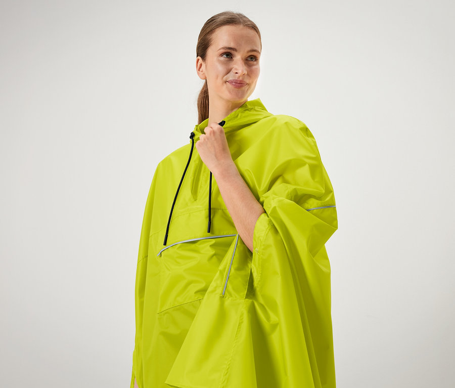 Kobieta trzyma kołnierz neonowo zielonego poncza.