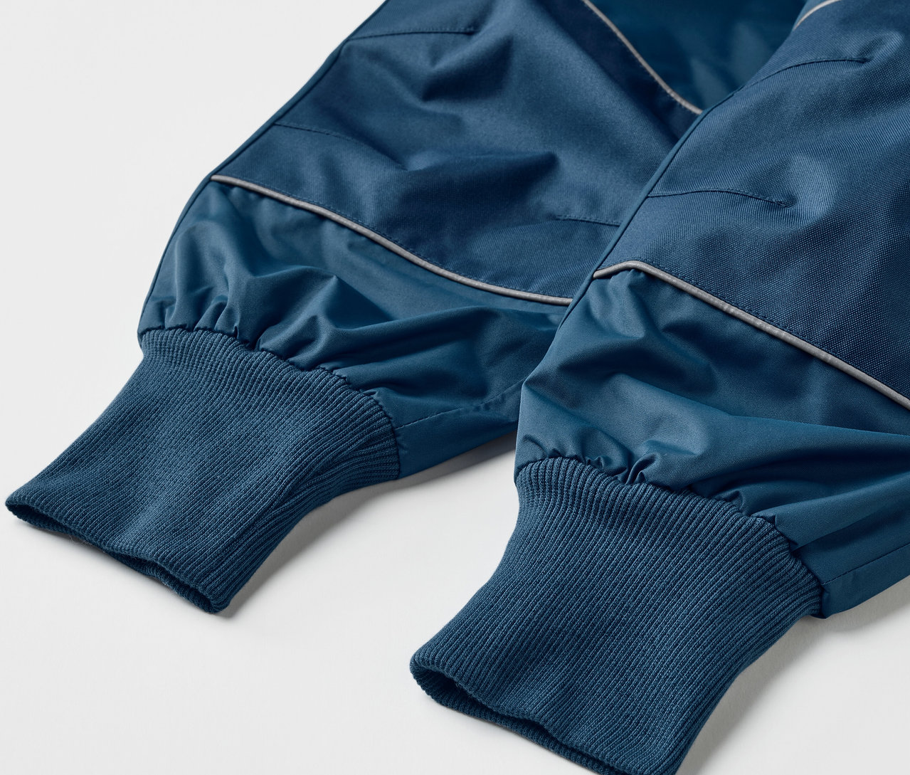 Zbliżenie na niebieskie spodnie przeciwdeszczowe rosnące wraz z dzieckiem.