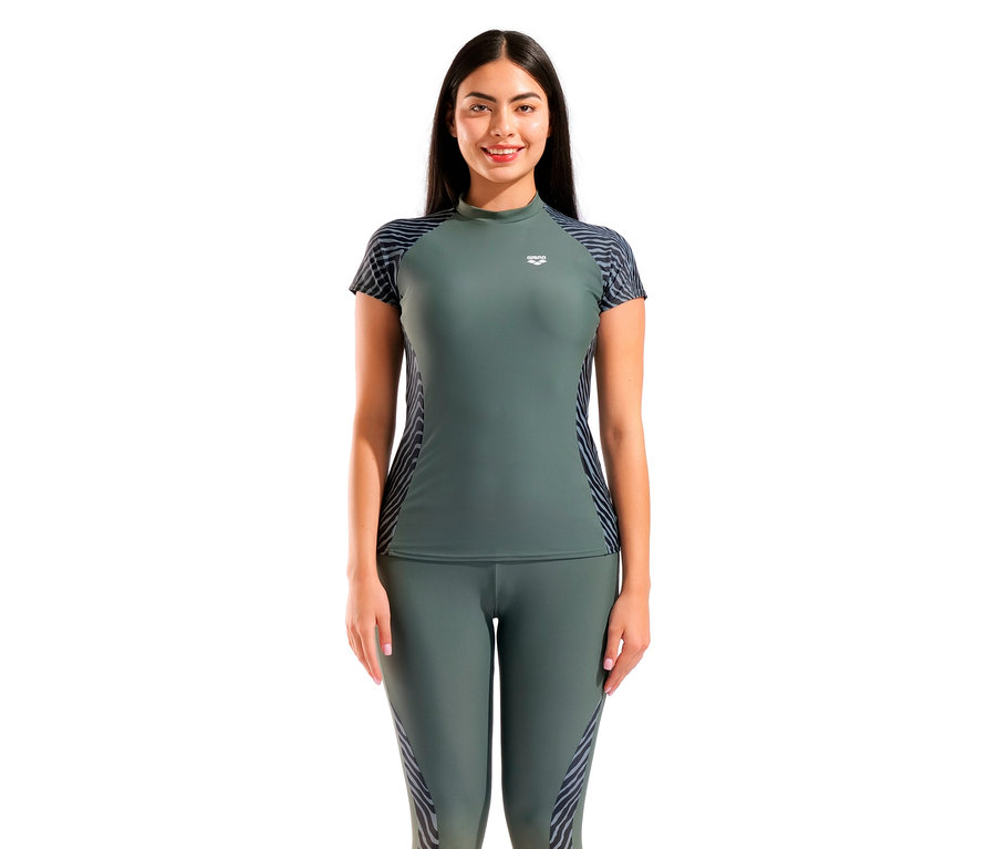 Kobieta ma na sobie zieloną koszulkę z krótkim rękawem Arena i legginsy w zebrę.