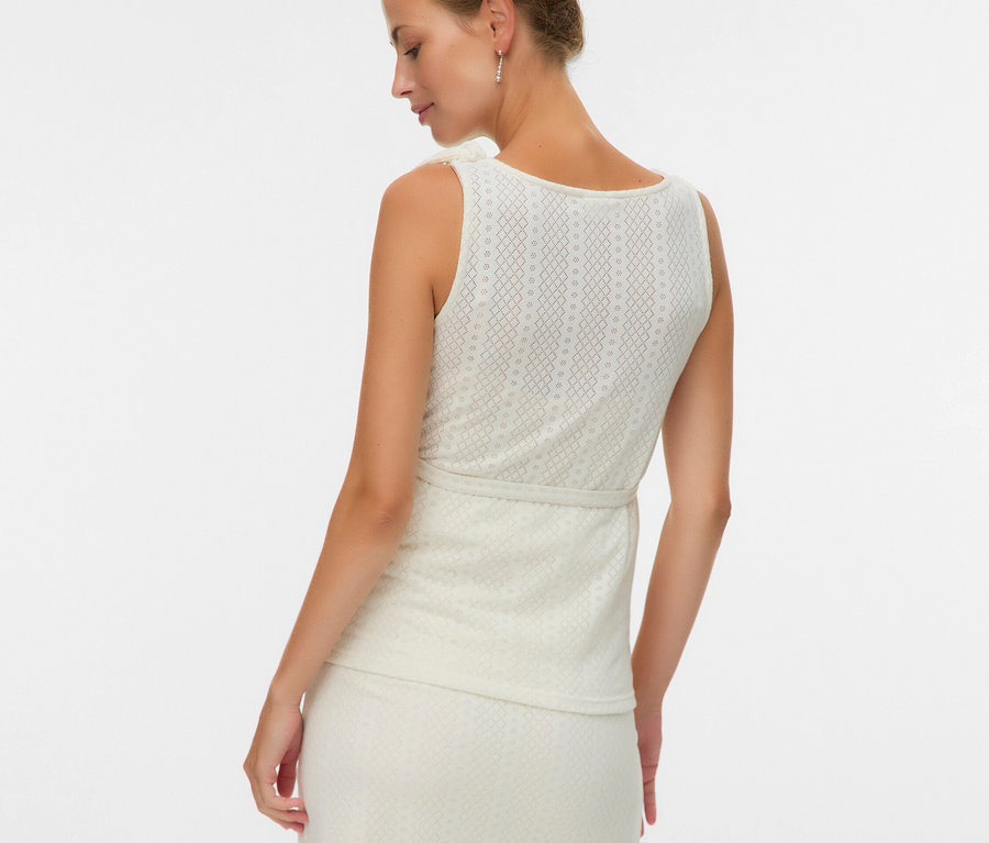 Kobieta od tyłu w bluzce bez rękawów i spódnicy we wzory.