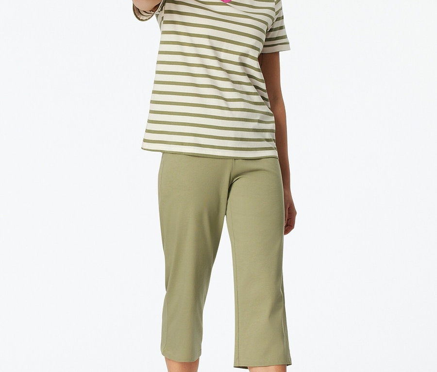 Kobieta stoi boso, ubrana w paski t-shirt z dekoltem w serek i zielone spodnie capri.