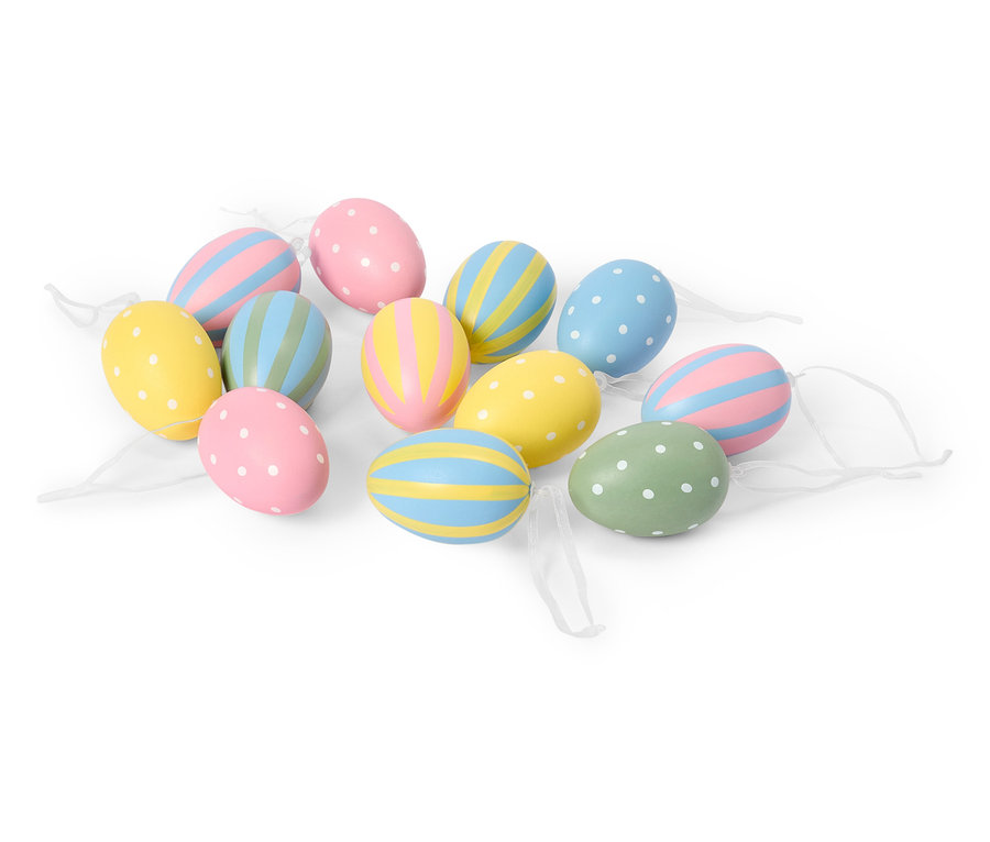Na białym tle leży kilka pastelowych jajek wielkanocnych z kropkami i paskami.