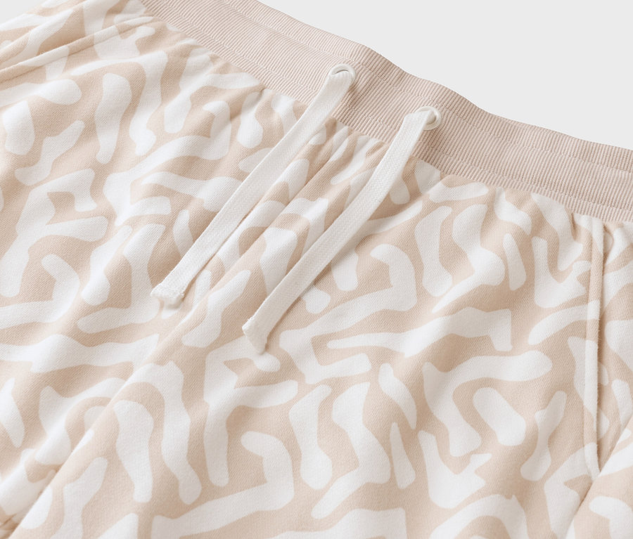 Zbliżenie beżowych spodni we wzory z białym sznurkiem.