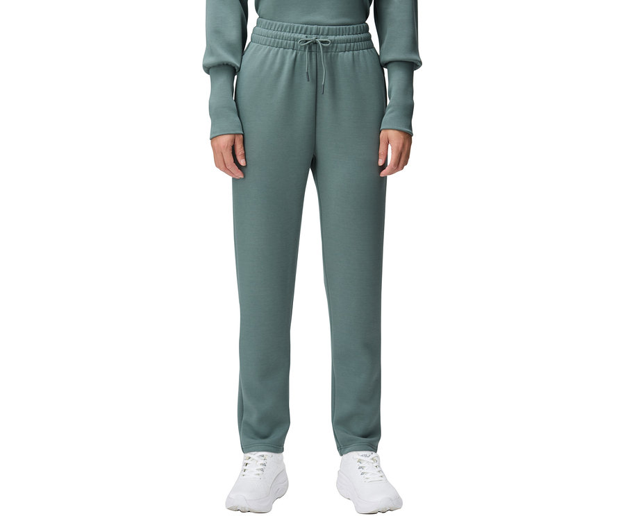 Osoba nosi zielone spodnie dresowe i białe trampki.