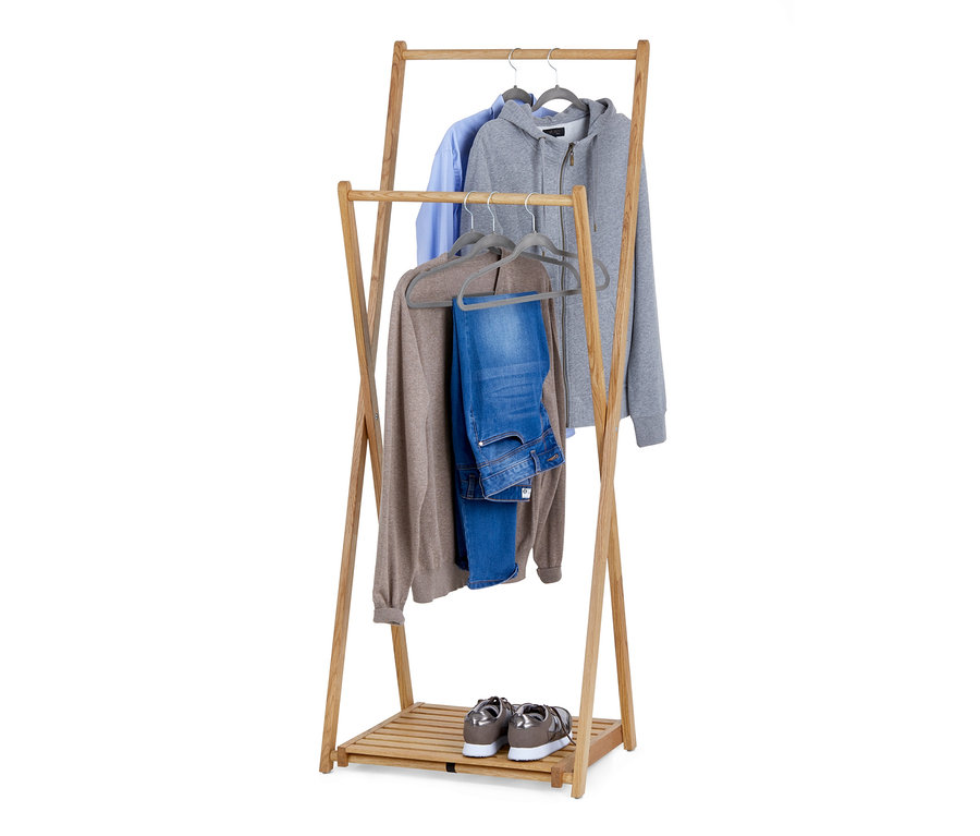 Składany wieszak na ubrania z litego drewna z koszulą, bluzą z kapturem, swetrem i dżinsami na wieszakach. Na dolnej półce stoją buty.
