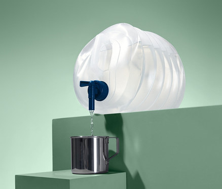 Woda leje się ze składanego kanistra do metalowego kubka.