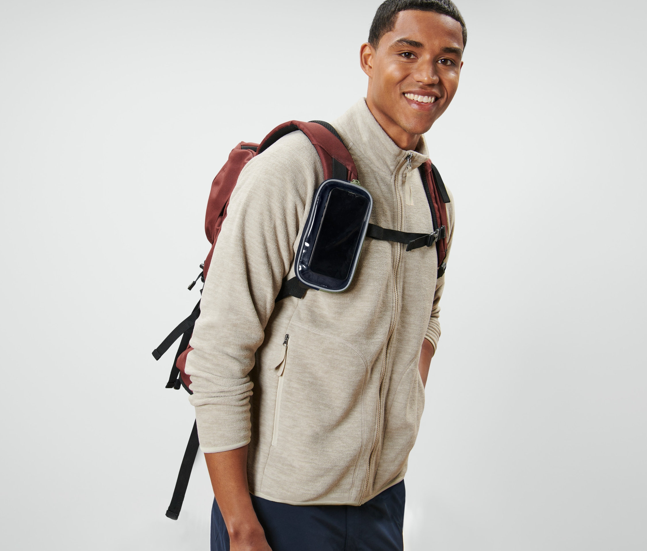 Uśmiechnięty mężczyzna z plecakiem i wielofunkcyjną torebką z okienkiem.