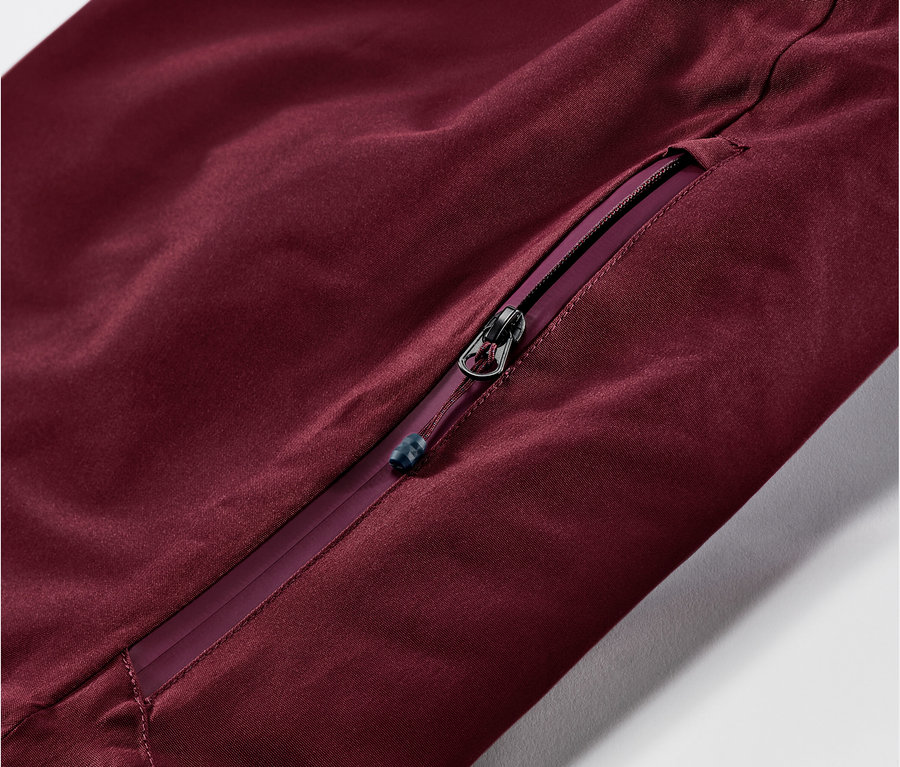 Detal bordowych spodni narciarskich i snowboardowych z zamkiem błyskawicznym.