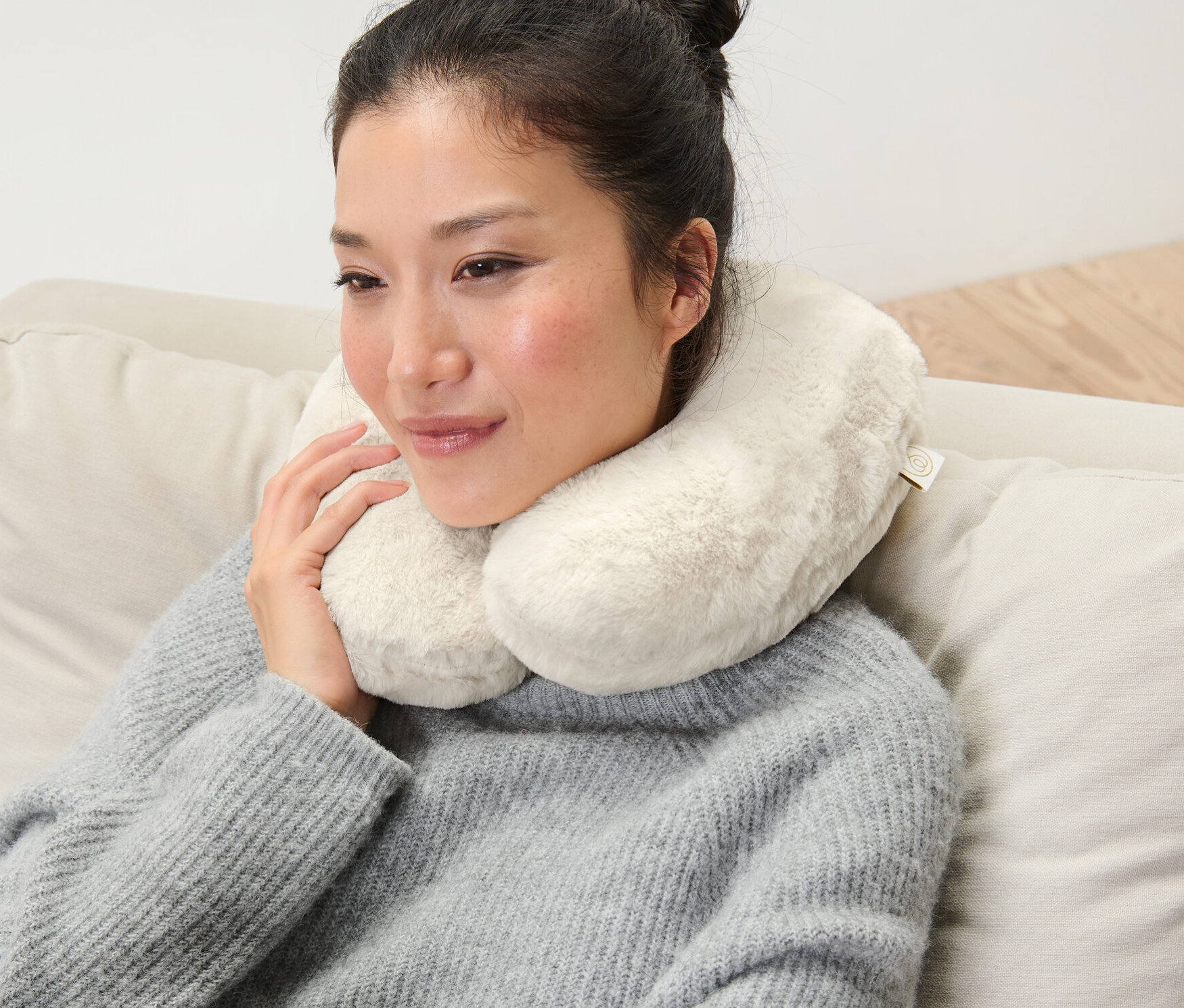 Kobieta siedzi na kanapie z poduszką na kark z pianki memory.