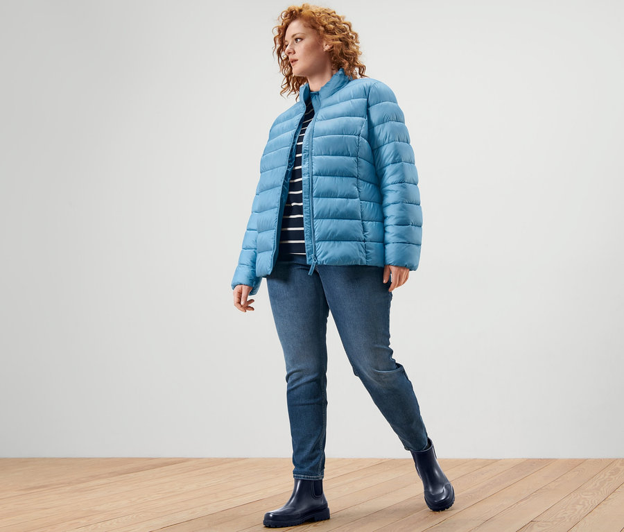 Kobieta ma na sobie kurtkę pikowaną, bluzkę z rękawem o długości 3/4 i tregginsy »Fit Nelly«.