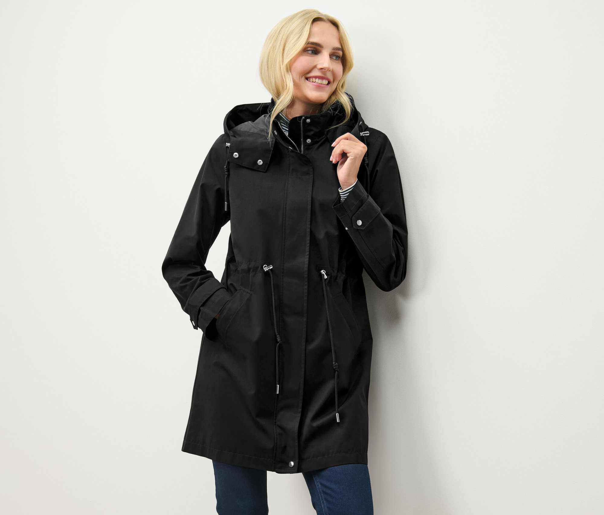 Blondynka pozuje w czarnej parce z kapturem.