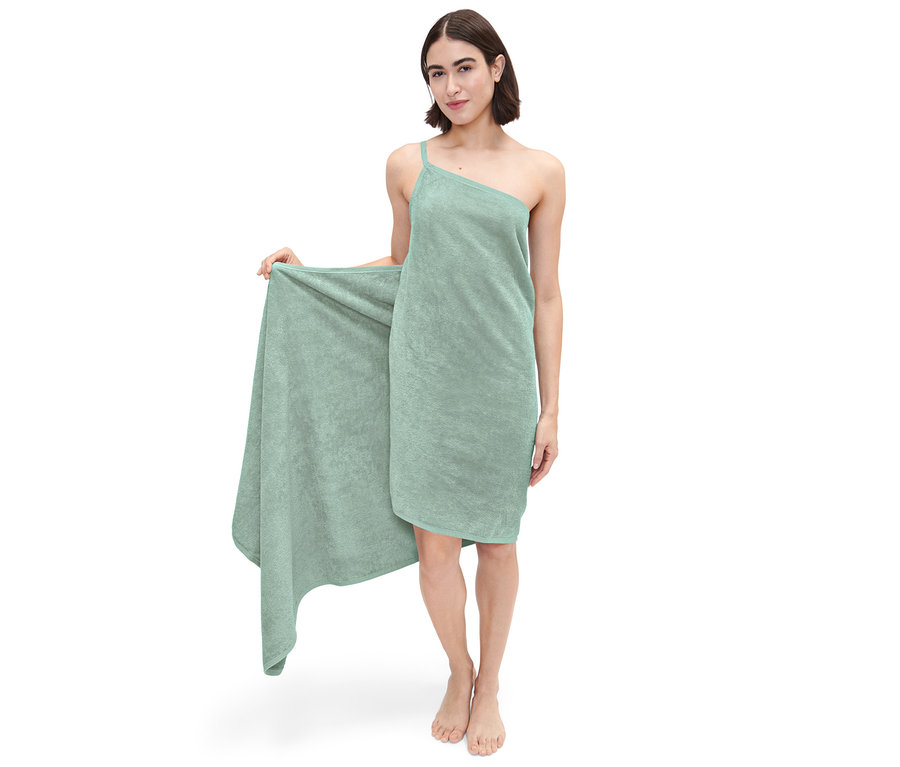 Kobieta pozuje w zielonej sukience ręcznikowej.